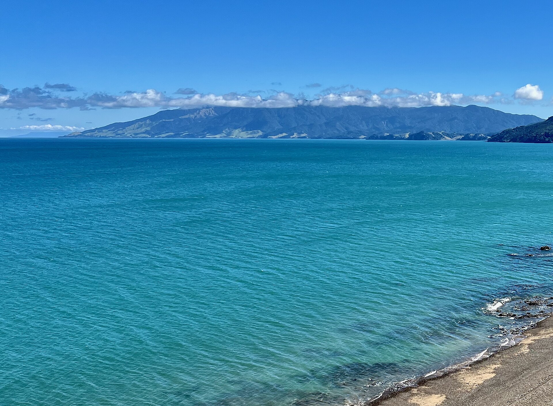 Turquoise water off the western Coromandel coast near Amodeo Bay, with the Moehau Range beyond